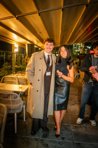 Two attendees posing together on the terrace at night