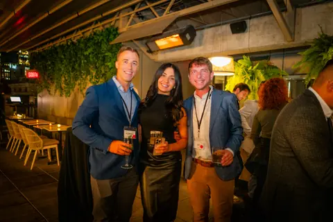 Three attendees with event lanyards posing together at the close of the ElevateOS Montreal event