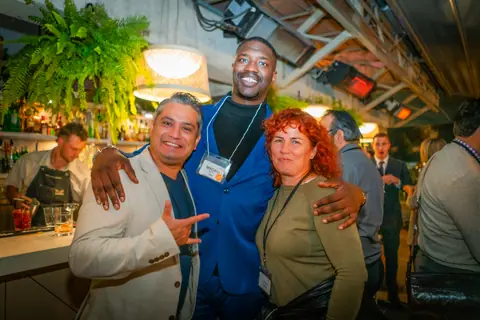 Three attendees posing arm in arm by the bar at the end of the night
